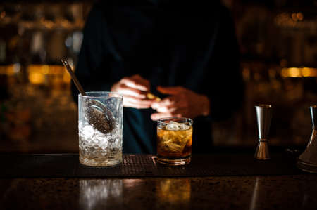 Jar of ice and a glass filled with a fresh summer cocktail arranged on the bar counterの写真素材