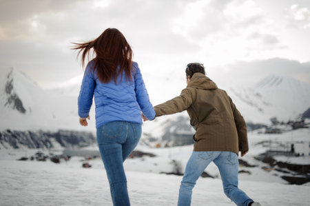 guy in a brown jacket holds a brunette girl in a blue jacket by the hand and leads for a walk...