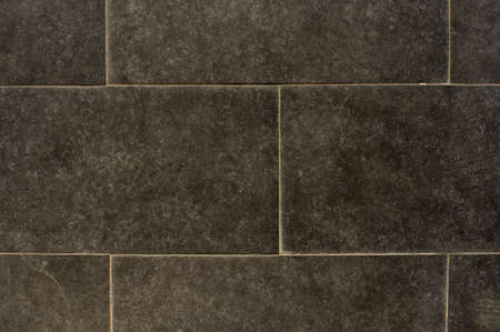 Close up photo of deep grey tiled marble exterior wall with lines between rectangle smooth tilesの写真素材
