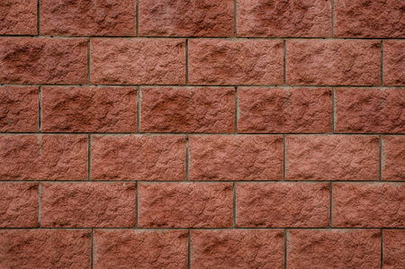 Close up background texture of rectangular red building bricks arranged in a wall with concrete