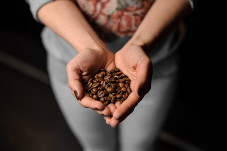 Young woman hands holding a big handful of fresh and aromatic coffee beans for making a drinkの写真素材