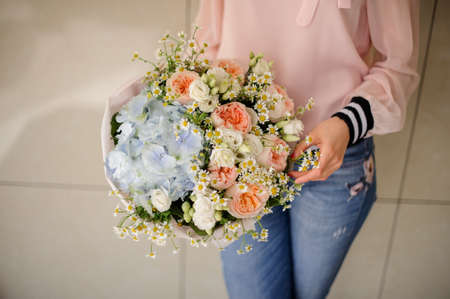 Girl holding in her hands a beautiful big bouquet of rose colour ranunculuses, camomiles and blue hydrangeasの写真素材
