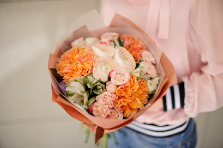 Girl in a pink shirt holding in her hands a beautiful bouquet of champaigne colour and white tender...