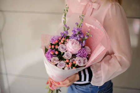 Girl in a pink shirt holding in her hands a beautiful bouquet of bright violet and pink tender flowersの写真素材