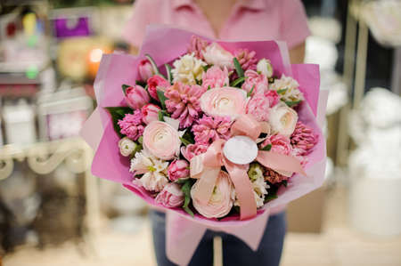 Girl in pink shirt holding in her hands a beautiful big bouquet of pink tender spring flowersの写真素材