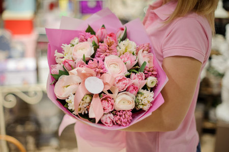 Girl in a pink shirt holding in her hands a beautiful big bouquet of rose colour tender flowersの写真素材