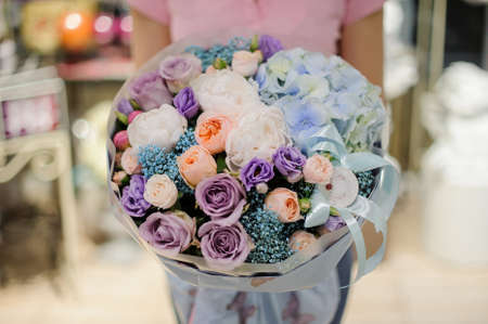 Woman holding a large bouquet in blue and purple tones consisting of roses, peonies and other lovely flowersの写真素材