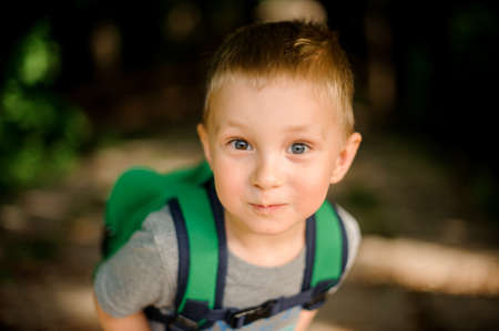 Happy cute little boy with a green backpackの写真素材