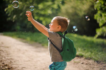 Little boy playing with soap bubbles in a green summer park on the sunny dayの写真素材
