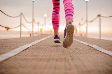 Close up photo of woman legs running over the wooden bridge during the morning sunriseの写真素材