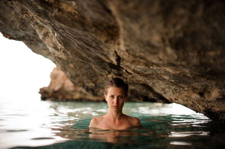 Photo of a beautiful young girl with redhead tied hair in the water cave inside the mountainの写真素材