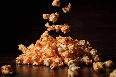Delicious salty golden popcorn pile isolated on the black background. Popcorn falling down on the dark backgroundの写真素材