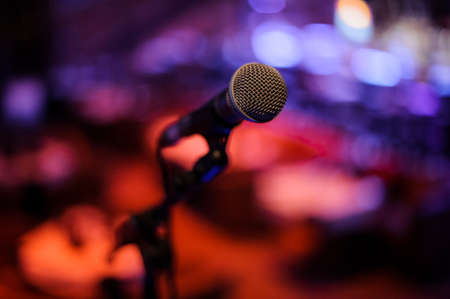 Microphone with metal body in holder on the blurred red and blue background in the night clubの写真素材