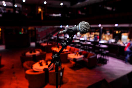 Microphone with metal body in the holder on the blurred red background of the night clubの写真素材
