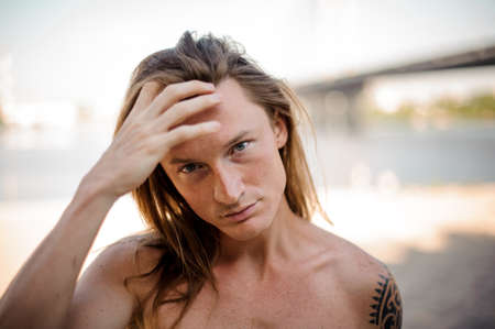 Portrait of young long and red haired man spending time on the beach on summer dayの写真素材