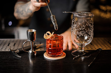 Bartender stirring a fresh red cocktail with a spoon in the form of a finger