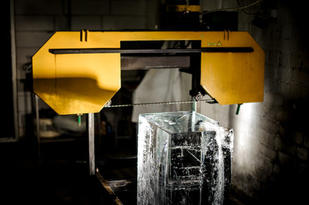 Big clear ice cube standing on the floor under the yellow equipment element on the ice production plantの写真素材