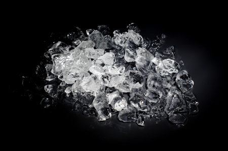 Heap of a small white and transparent ice cubes isolated on the black background starts melt