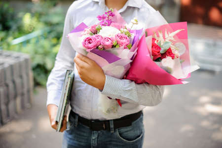Schoolboy holding two festive pink bouquet of flowersの写真素材