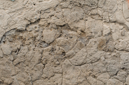 Macro photo of an old shabby concrete exterior wall with peeled off pieces of it
