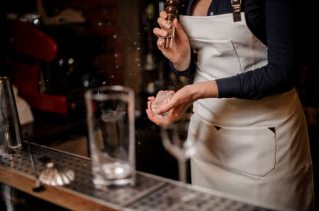 Sexy barmaid with a deep neckline crushing a piece of ice for making fresh summer cocktailの写真素材