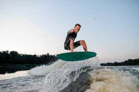 Wakesurfer riding down the river on a blue wake board against the background of sky