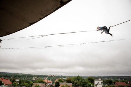 Brave woman balancing high on a slackline against the grey sky on rainy summer day