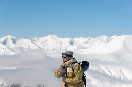 man in protective ski goggles and a warm suit, with a snowboard in his hands, rises to the track
