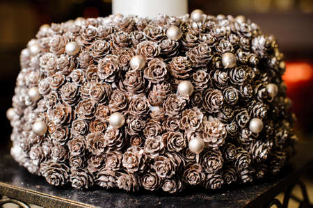 Christmas candlestick made of fir cones and little decorative white balls covered with artificial snowの写真素材