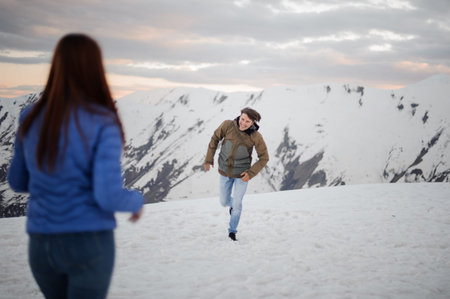 Young man running to her girlfriend in the high mountains having fun on winter vacations