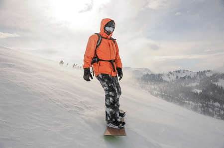 Man riding down the mountain hill on the snowboard on the background of sky in the mountain tourist resort in Goderzi, Georgiaの写真素材