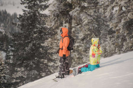 Two snowboarders standing back to back on the mountain slope in the popular tourist resort in Goderzi, Georgiaの写真素材