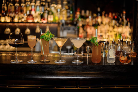Many different delicious cocktails in a line on the bar counter on the blurred background of the bar