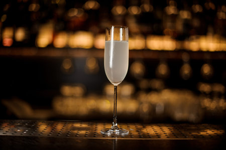Glass of a delicious cocktail French 75 standing on the bar counter