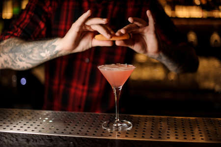 Barman sprinkling orange peel juice into a Cosmopolitan cocktailの写真素材