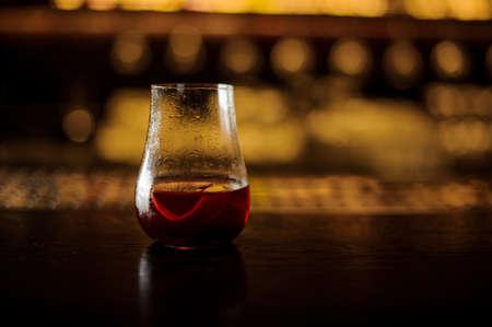 Sazerac cocktail decorated with orange zest standing on the steel and wood bar counter on the blurred backgroundの写真素材