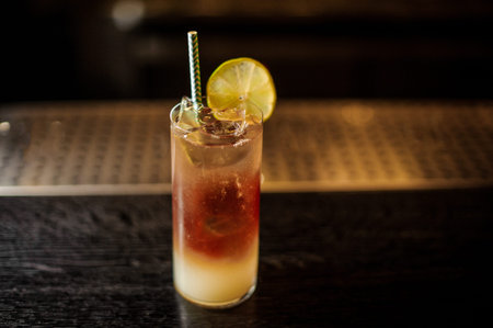 View from above Dark Stormy cocktail decorated with lime slice standing on the steel and wood bar...