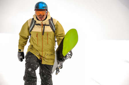 Man walking with the black and green snowboard in the mountain in the popular tourist resort in Georgiaの写真素材