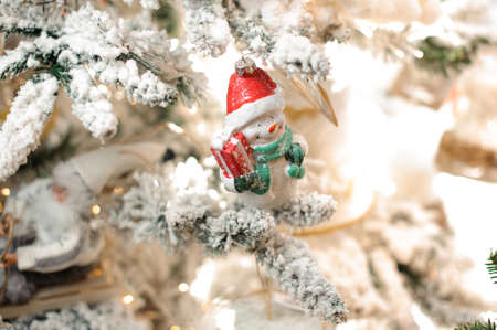 New year background of snow covered fir tree with white toy snowman and christmas decorationの写真素材