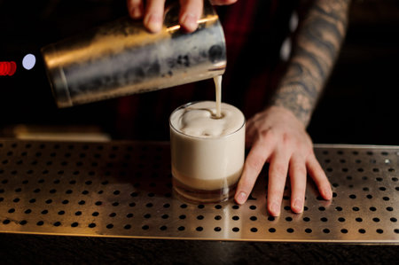 Bartender pouring fresh thick creamy alcoholic drink into a glass
