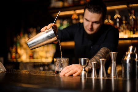 Professional bartender pouring a cocktail from the steel shakerの写真素材
