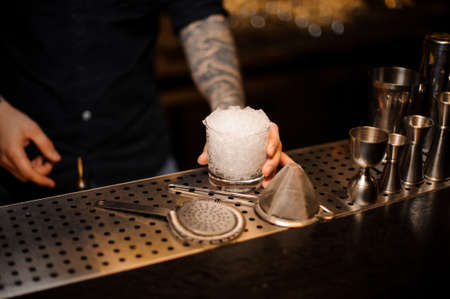 Man holding a glass of crushed ice standing on the bar counterの写真素材