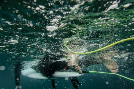 Brunette man in the black swimsuit swimming lying on a surf on the line up