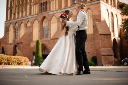 Happy and beautiful married couple dancing in the background of vintage red brick building withの写真素材