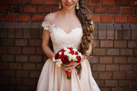 Smiling bride in white wedding dress with a bouquet of red and white rosesの写真素材