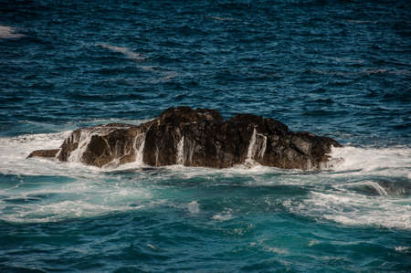 Raging sea with white waves around the rockの写真素材