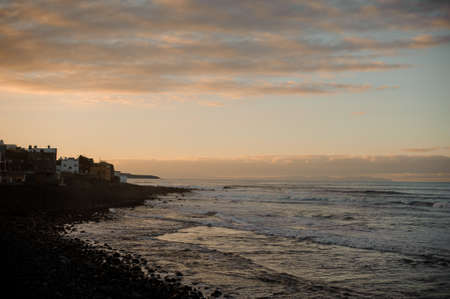 Twilight over ancient city and sea coast with waves under the skyの写真素材
