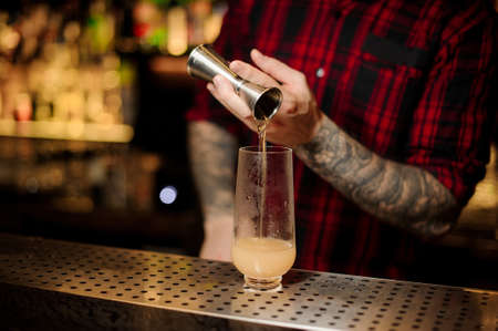 Bartender pouring a portion of alcoholic drink using jiggerの写真素材