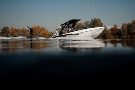Girl riding on the wakeboard on the high wave of the motorboatの写真素材