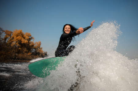Brunette girl jumping on the green wakeboard on the bending kneesの写真素材